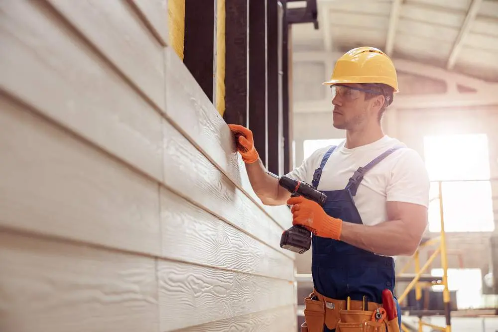 Handsome Young Man Builder Installing Exterior Wood Siding