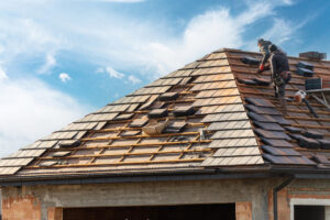Builder Working On Rooftop Of House On Construction Site